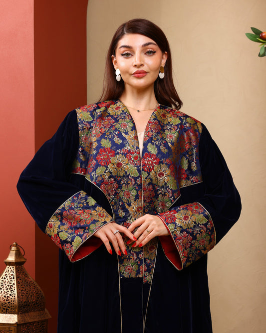 Woman wearing a floral embroidered abaya against a warm-toned background