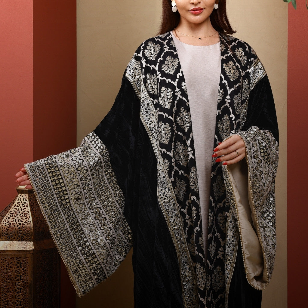 Woman wearing a black and white patterned abaya against a beige background