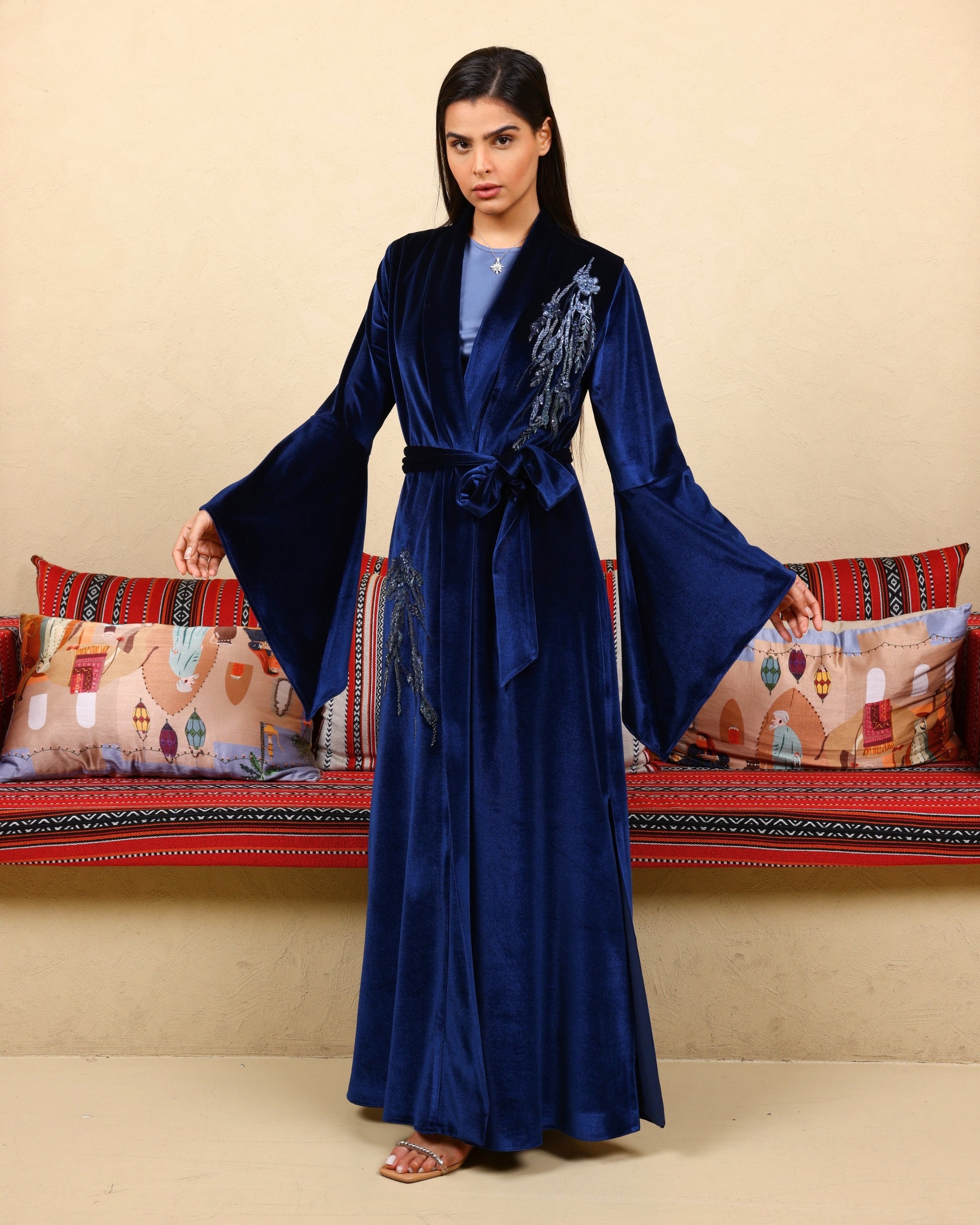 Woman wearing a blue embroidered robe in a decorated room.