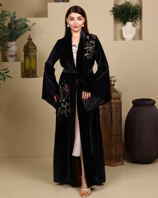 Woman wearing a black embroidered robe in an indoor setting with decorative elements.