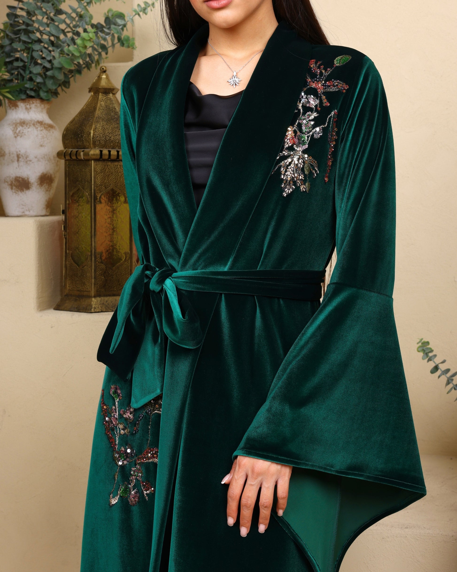 Green velvet robe with floral embroidery on a neutral background