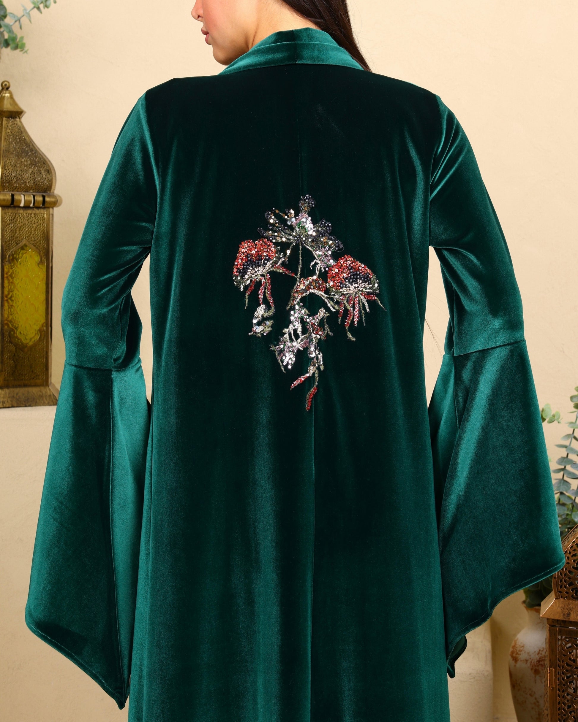 Green velvet coat with floral embroidery on the back, worn by a person.