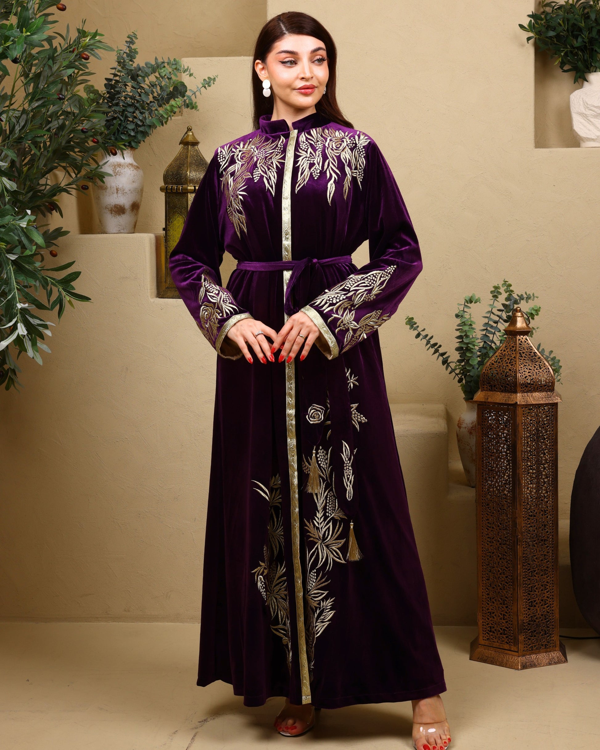 Woman wearing a long, dark purple embroidered dress in an indoor setting with decorative elements.
