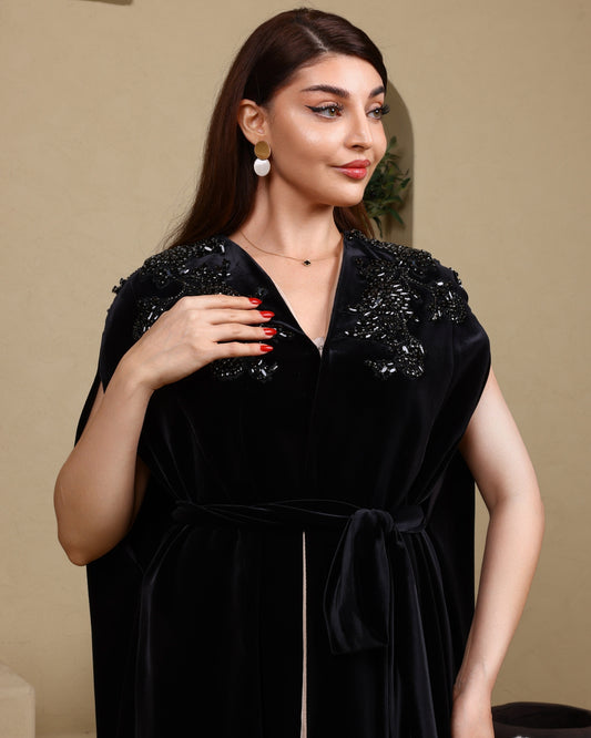 Woman wearing a black dress with embellishments against a beige background