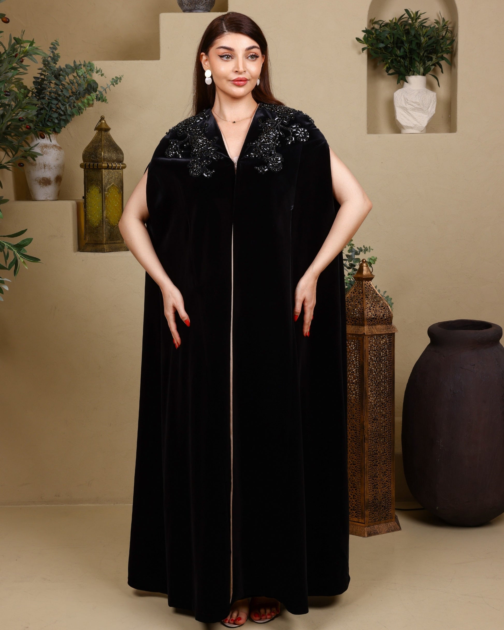 Woman wearing a black dress with floral embellishments in an indoor setting.