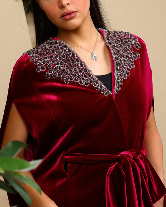 Red velvet dress with intricate lace collar worn by a model against a neutral background