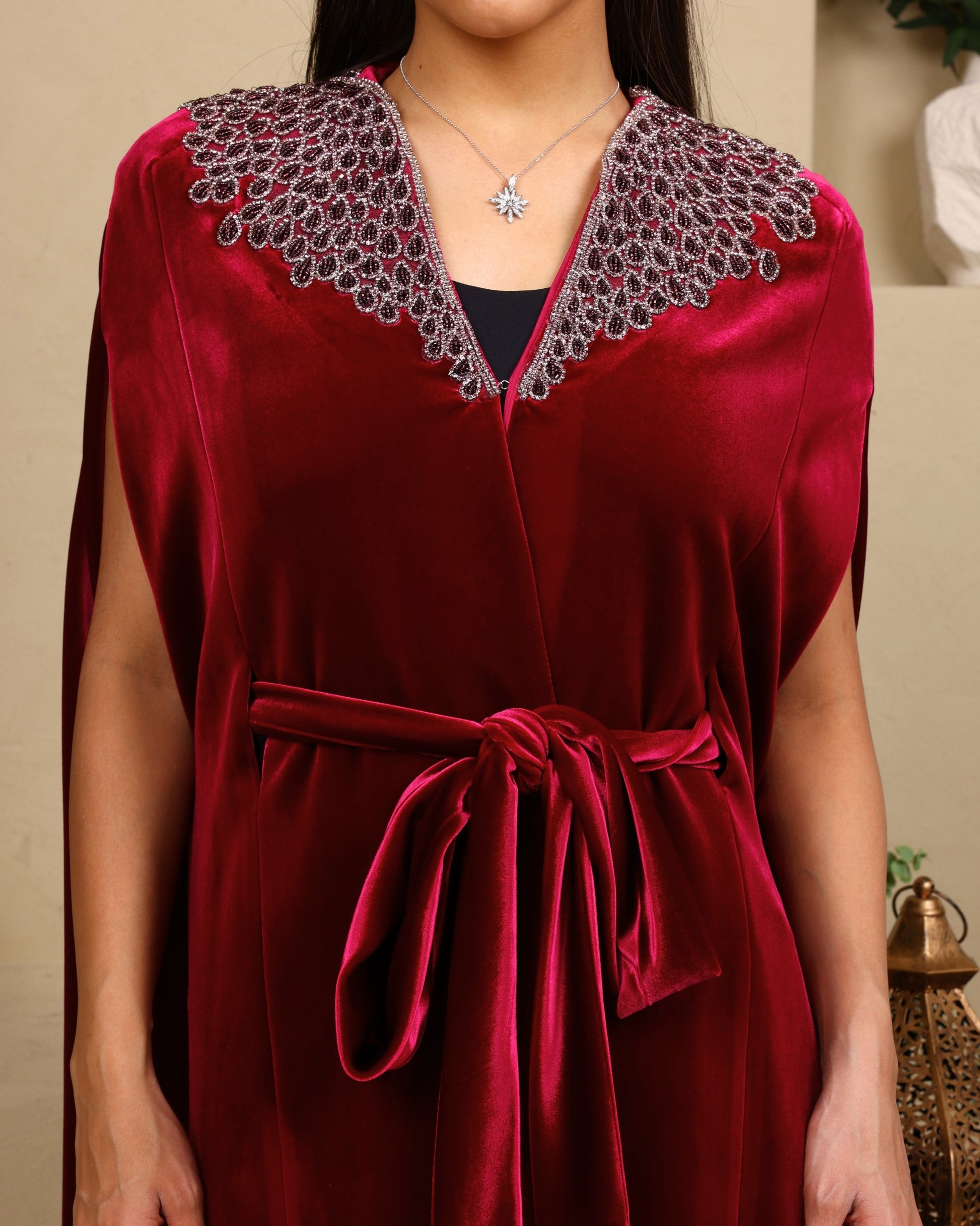 Red velvet dress with intricate lace collar worn by a person, against a neutral background.