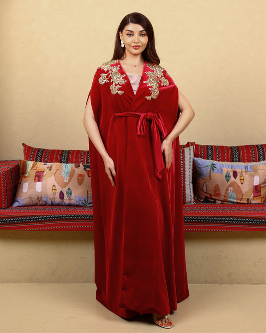 Woman wearing a red dress with gold embroidery in a decorated room.