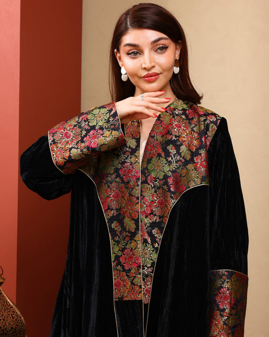 Woman wearing a black outfit with a floral patterned jacket against a beige background