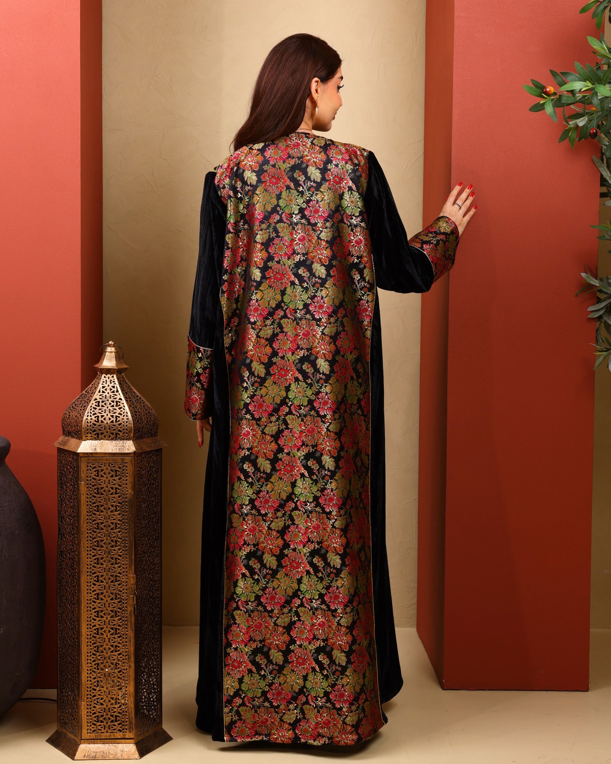 Woman wearing a floral dress with a black overlay against a red wall.