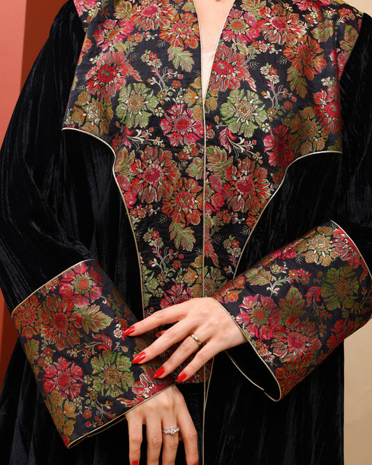 Close-up of a black garment with floral patterned sleeves and collar.