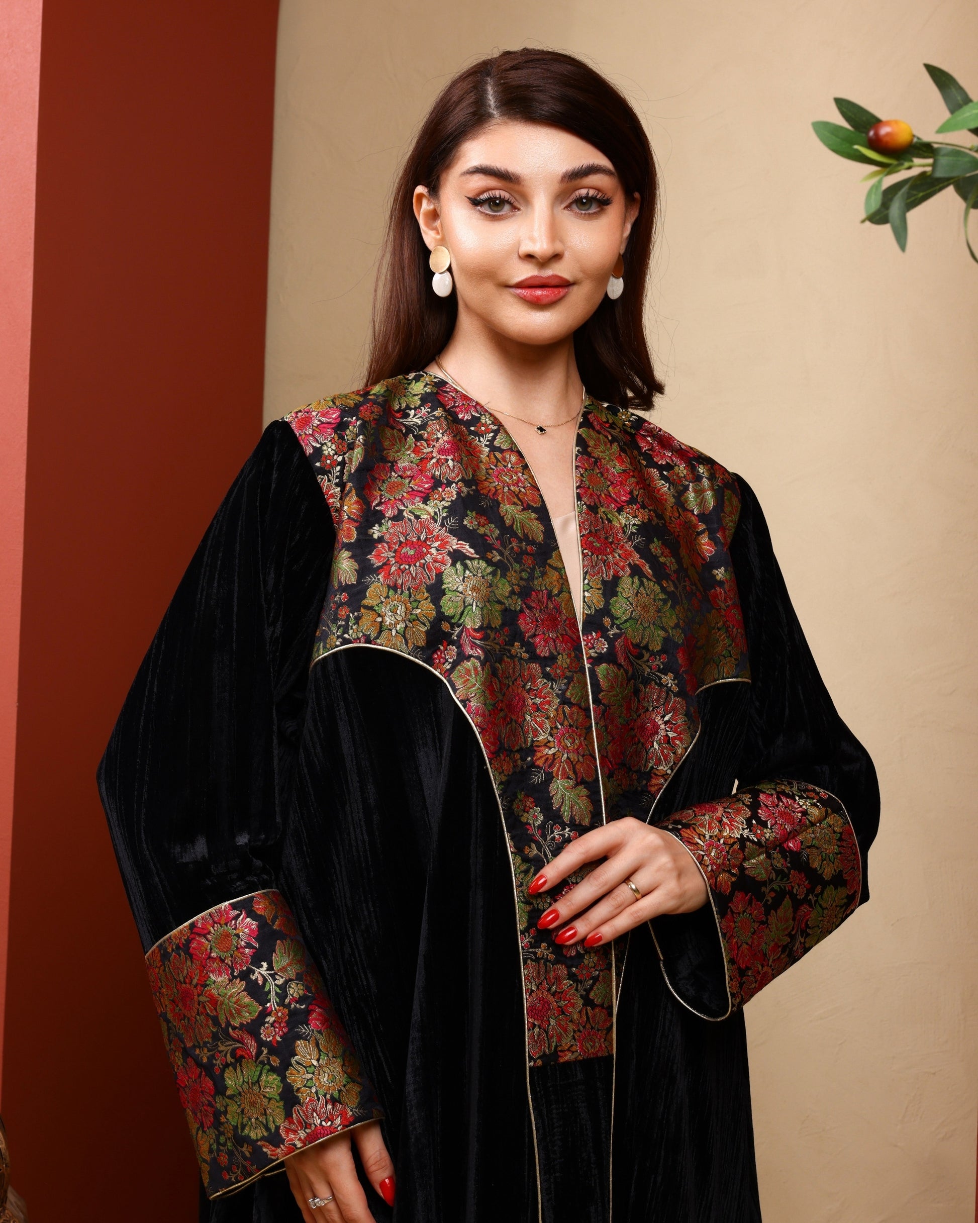 Woman wearing a black and floral traditional outfit against a beige background