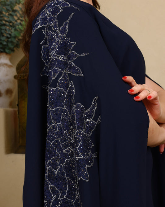 Navy blue garment with intricate white floral embroidery on a neutral background