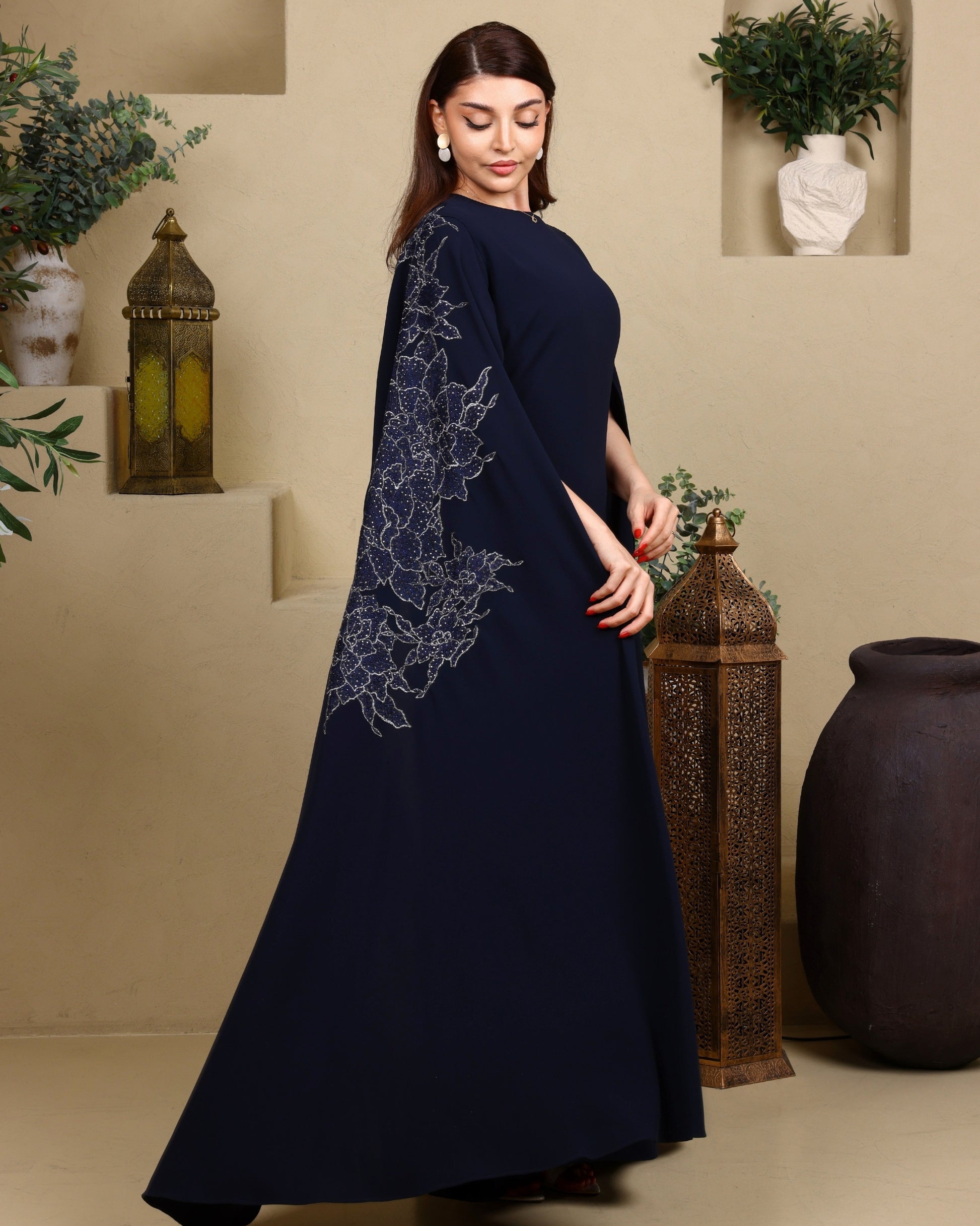 Woman wearing a navy blue dress with floral embroidery in a decorative setting.