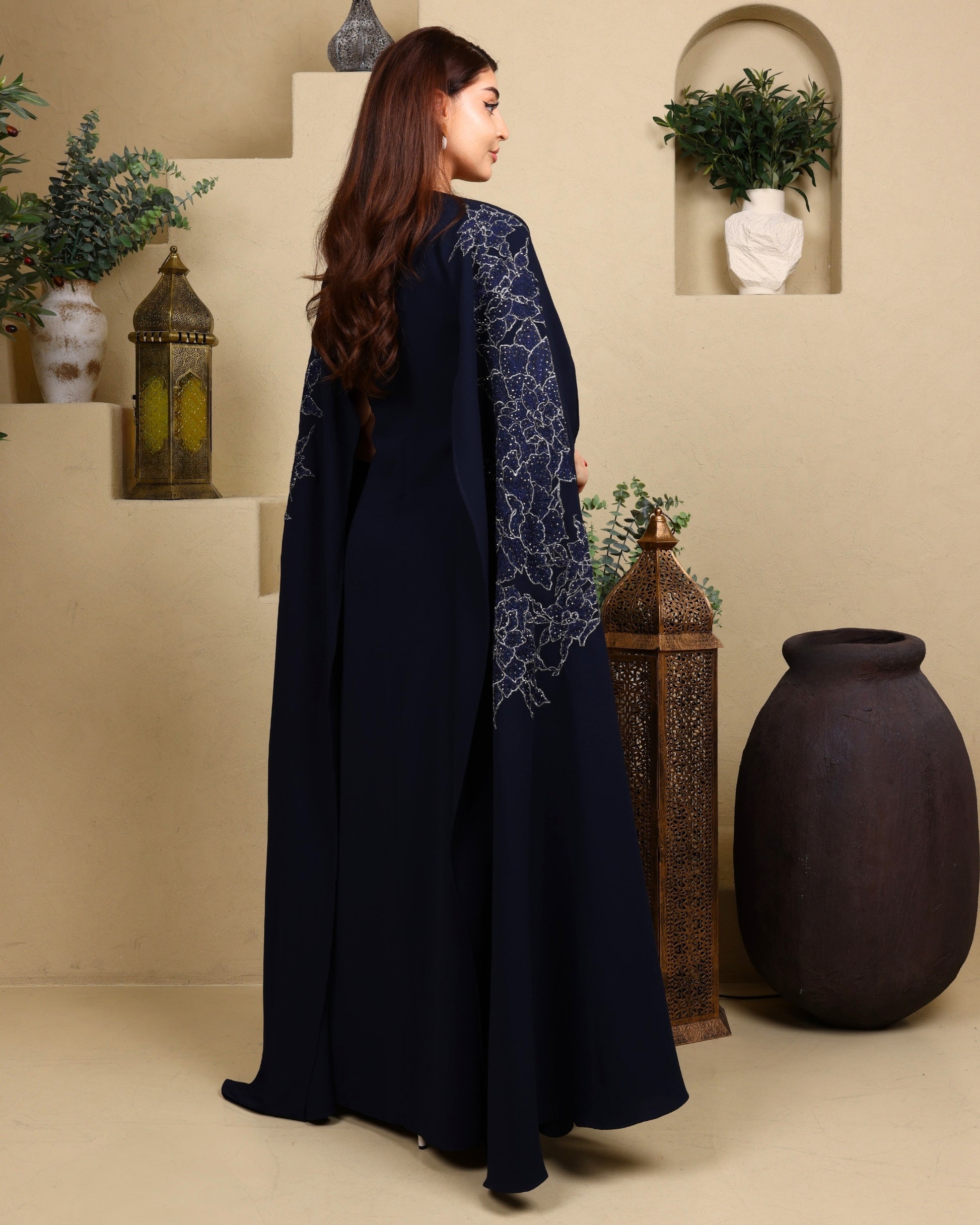 Woman wearing a navy blue dress with intricate patterns in a decorative setting.