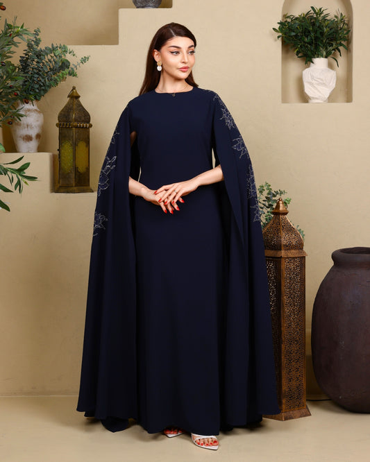 Woman wearing a navy blue dress with cape in a decorated indoor setting