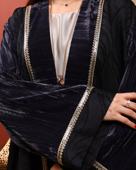 Dark gray velvet abaya with gold embroidery on a brown background