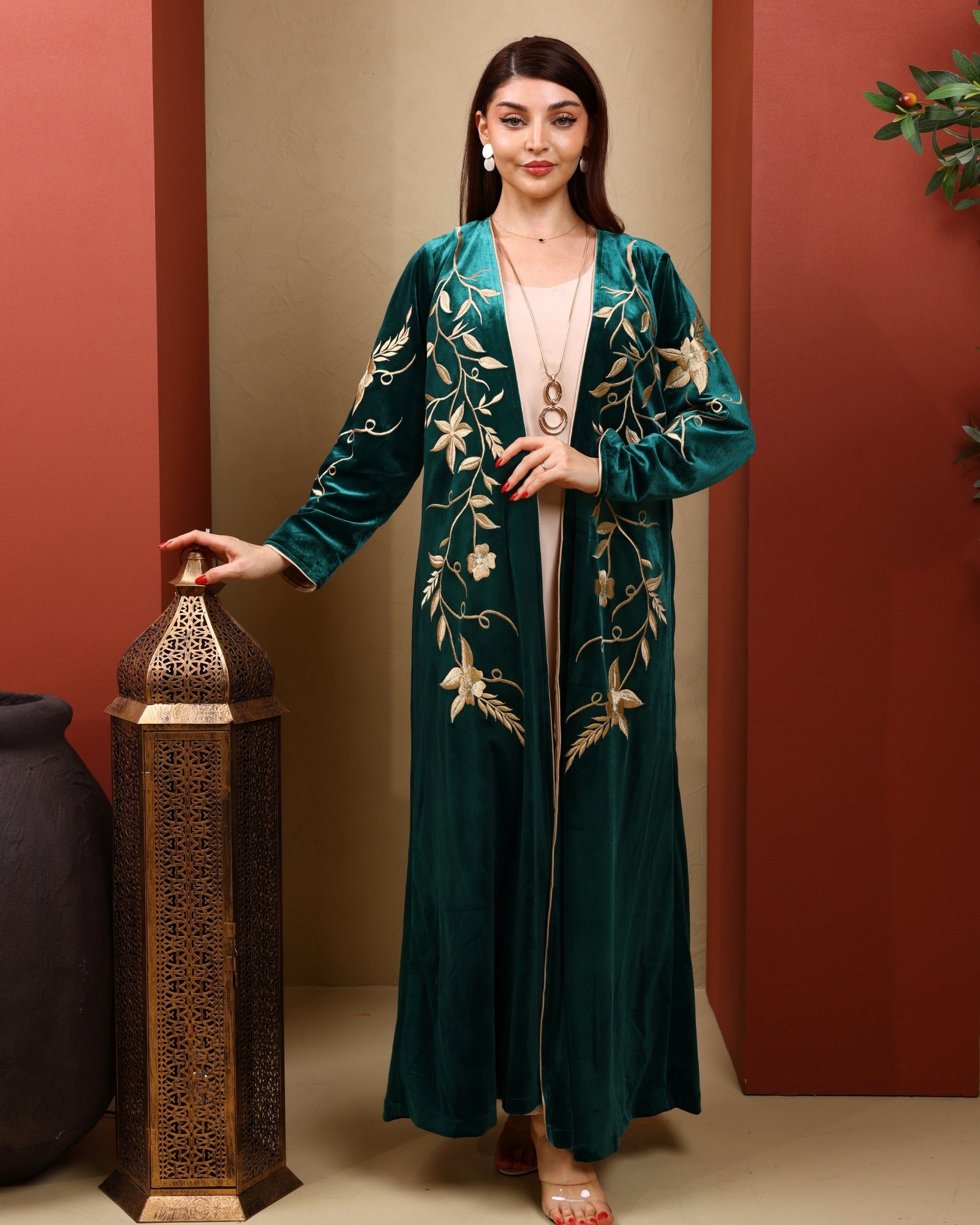 Woman wearing a green embroidered dress standing next to a decorative lantern.
