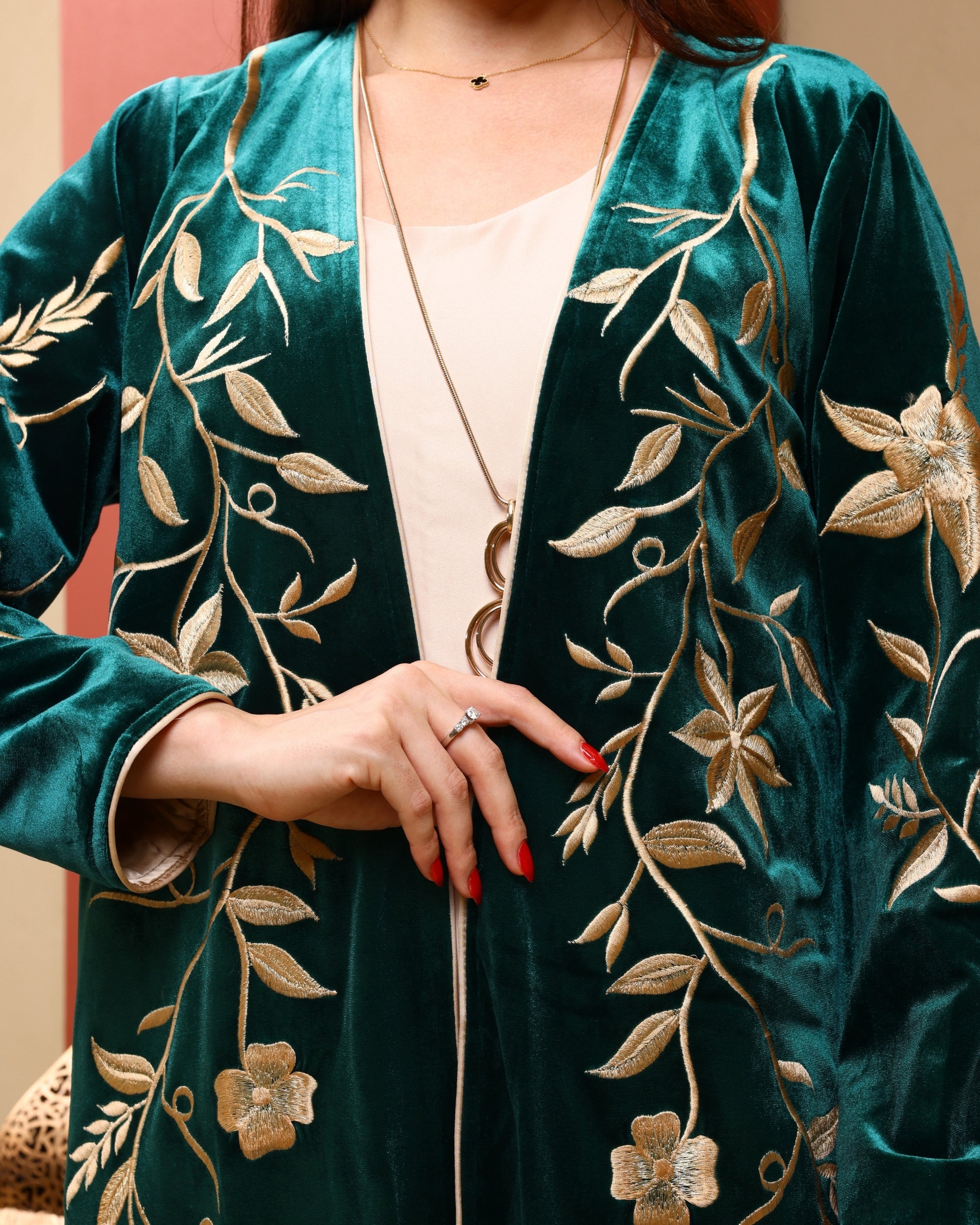 Green velvet cardigan with gold embroidery worn by a person.
