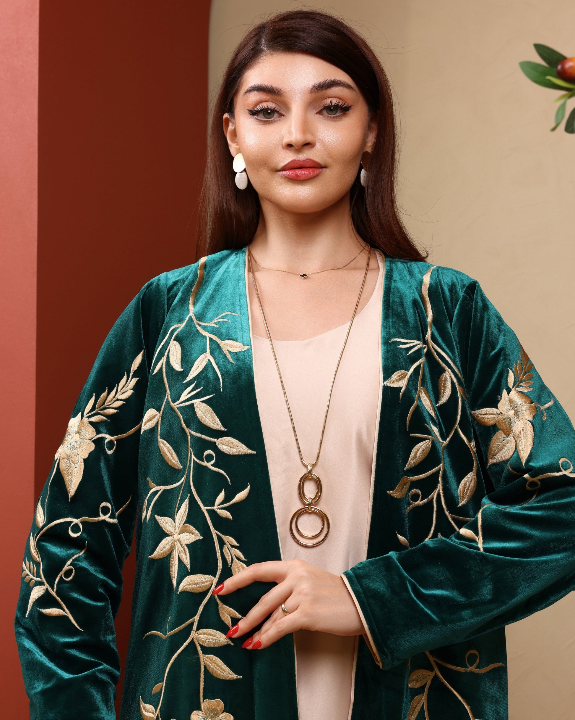 Woman wearing a green embroidered jacket with a beige background